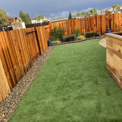 Backyard artificial grass lawn beside a raised timber planter