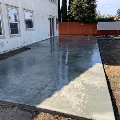 Colour-finished concrete patio still wet, running along the back of a house