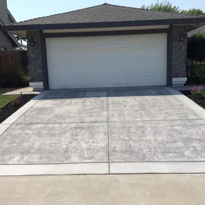 Finished broom-swept concrete driveway running up to a two-car garage