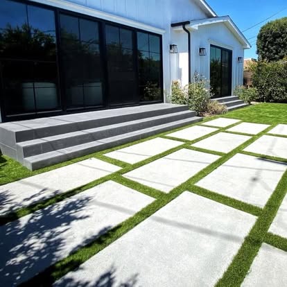 Large-format concrete pavers set as a grid with artificial grass joints between them