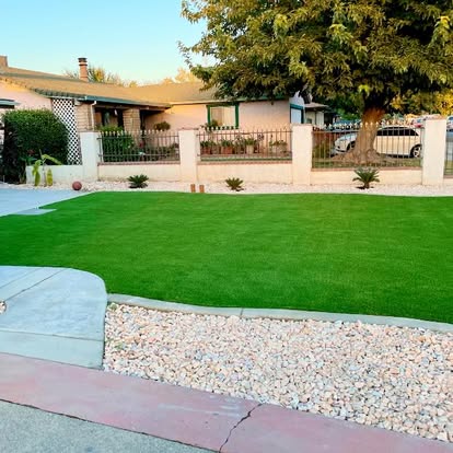 Wide front lawn laid in artificial grass, edged with concrete and white rock