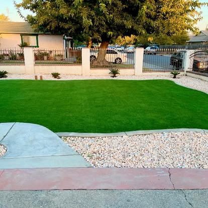 Front yard artificial grass lawn edged by a colour-finished concrete walkway and white rock