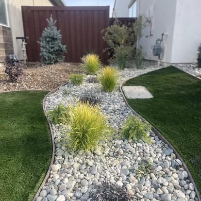 Finished front landscape combining river rock, ornamental planting, artificial grass and concrete pads