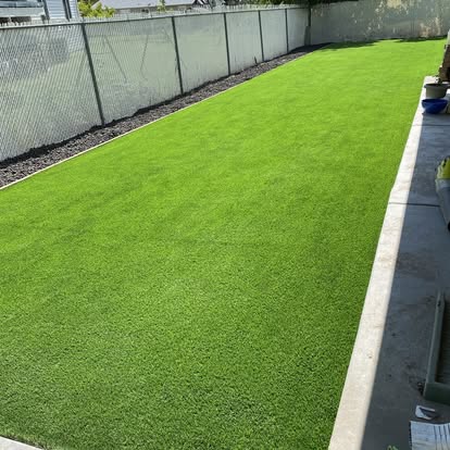 Long artificial grass lawn running the full length of a fence line