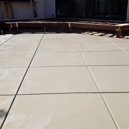 Finished patio slab beneath a timber pergola frame under construction