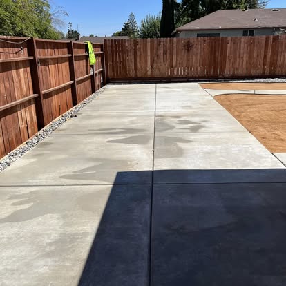 Concrete walkway running the length of a side yard against a fence