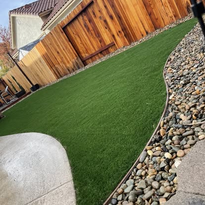 Side yard artificial grass strip bordered with cobble rock