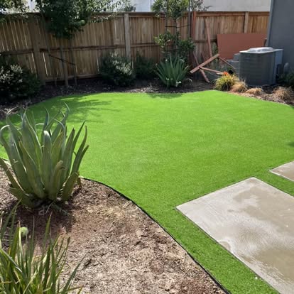 Artificial grass lawn edged by planting beds and a concrete pad
